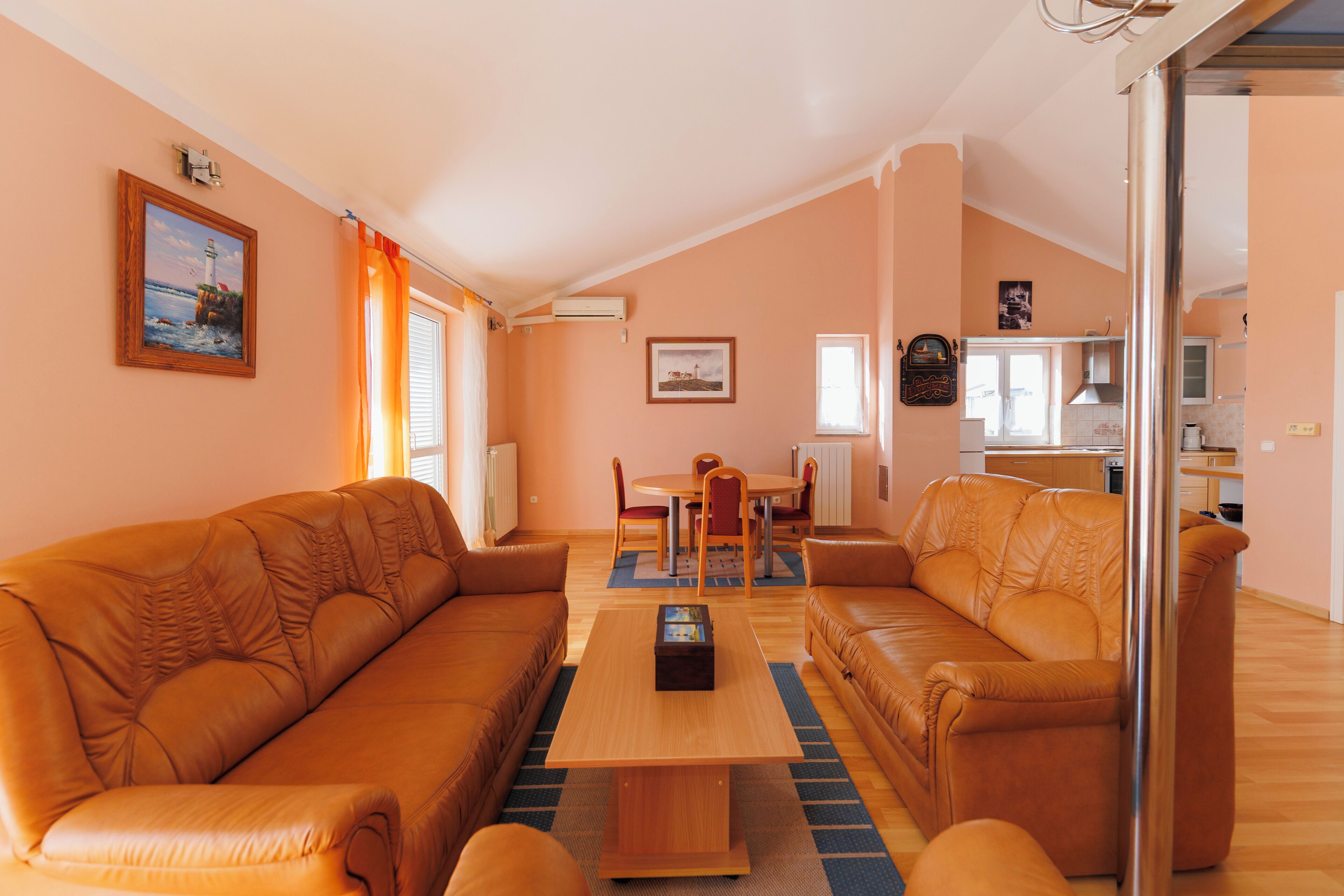 Una sala de estar con dos sofás, una mesa de centro y un comedor con una mesa y sillas.