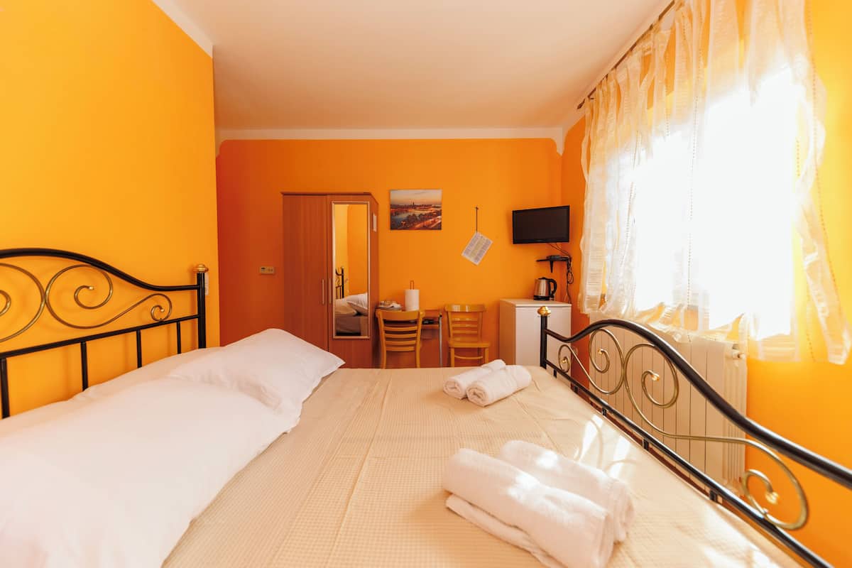 A hotel room with a bed, a desk, a chair, and a television.