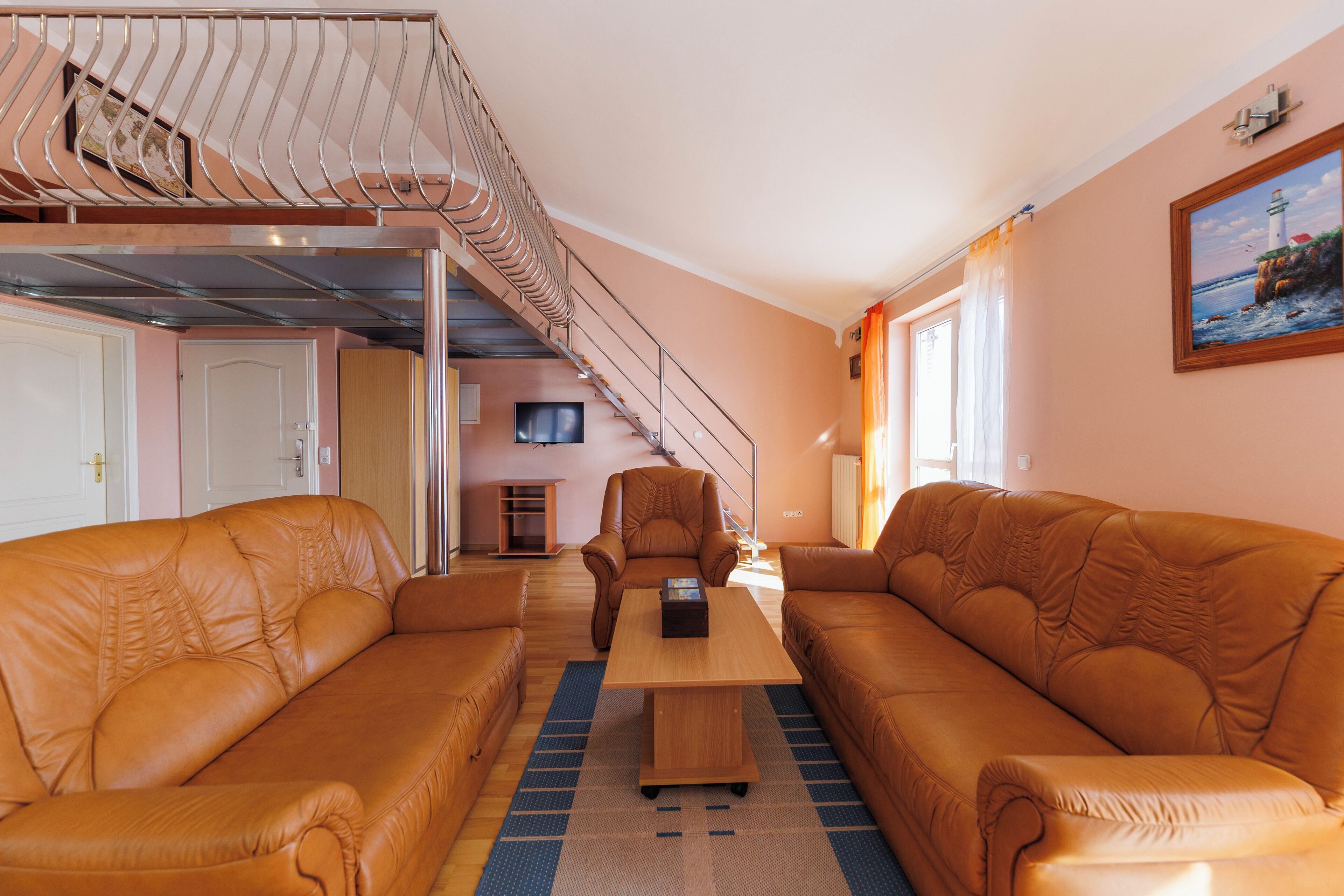 Una sala de estar con dos sofás de cuero, una mesa de centro de madera y una escalera que sube a un nivel superior.