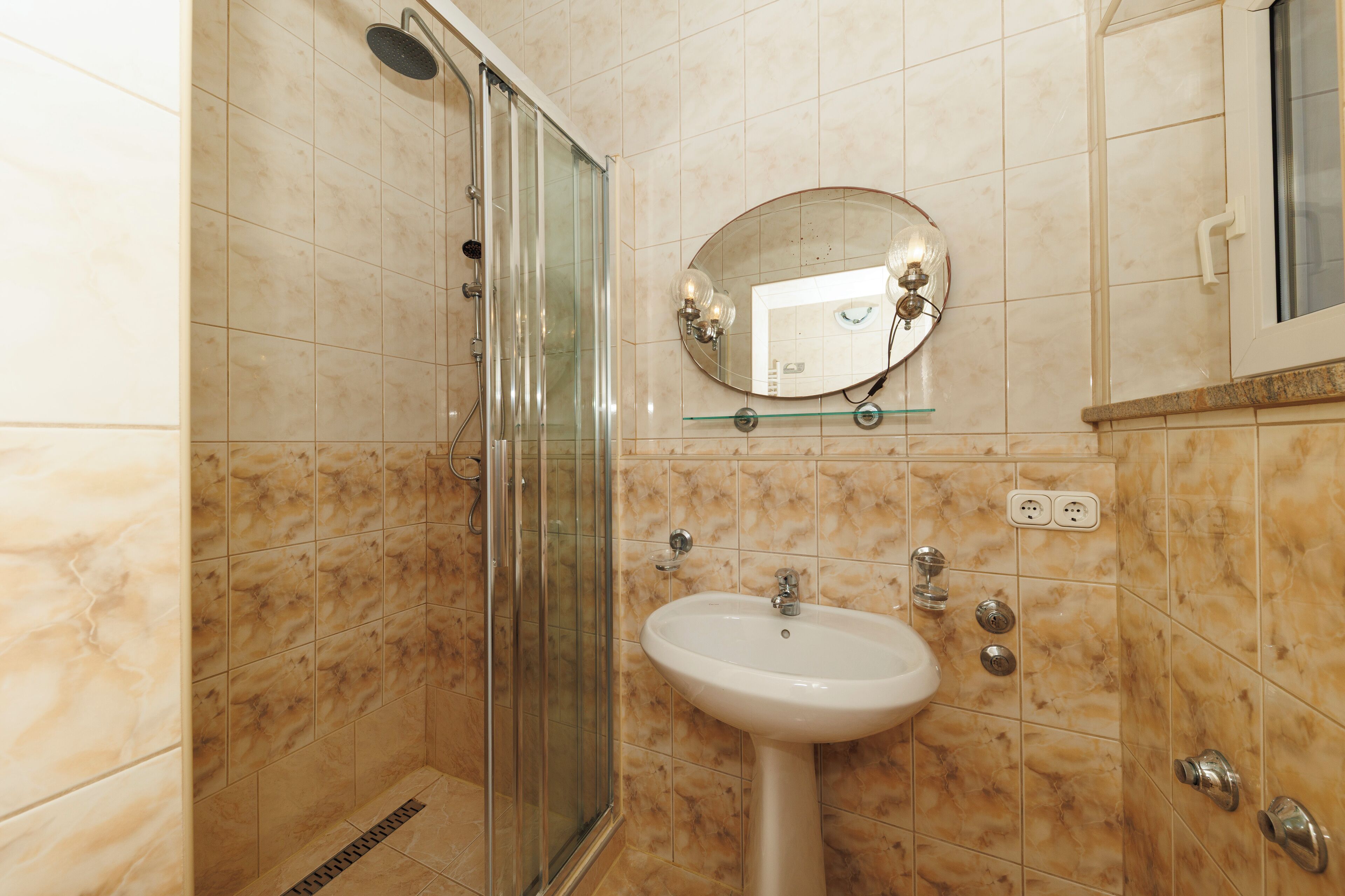Un bany amb dutxa de vidre, un lavabo i un mirall.