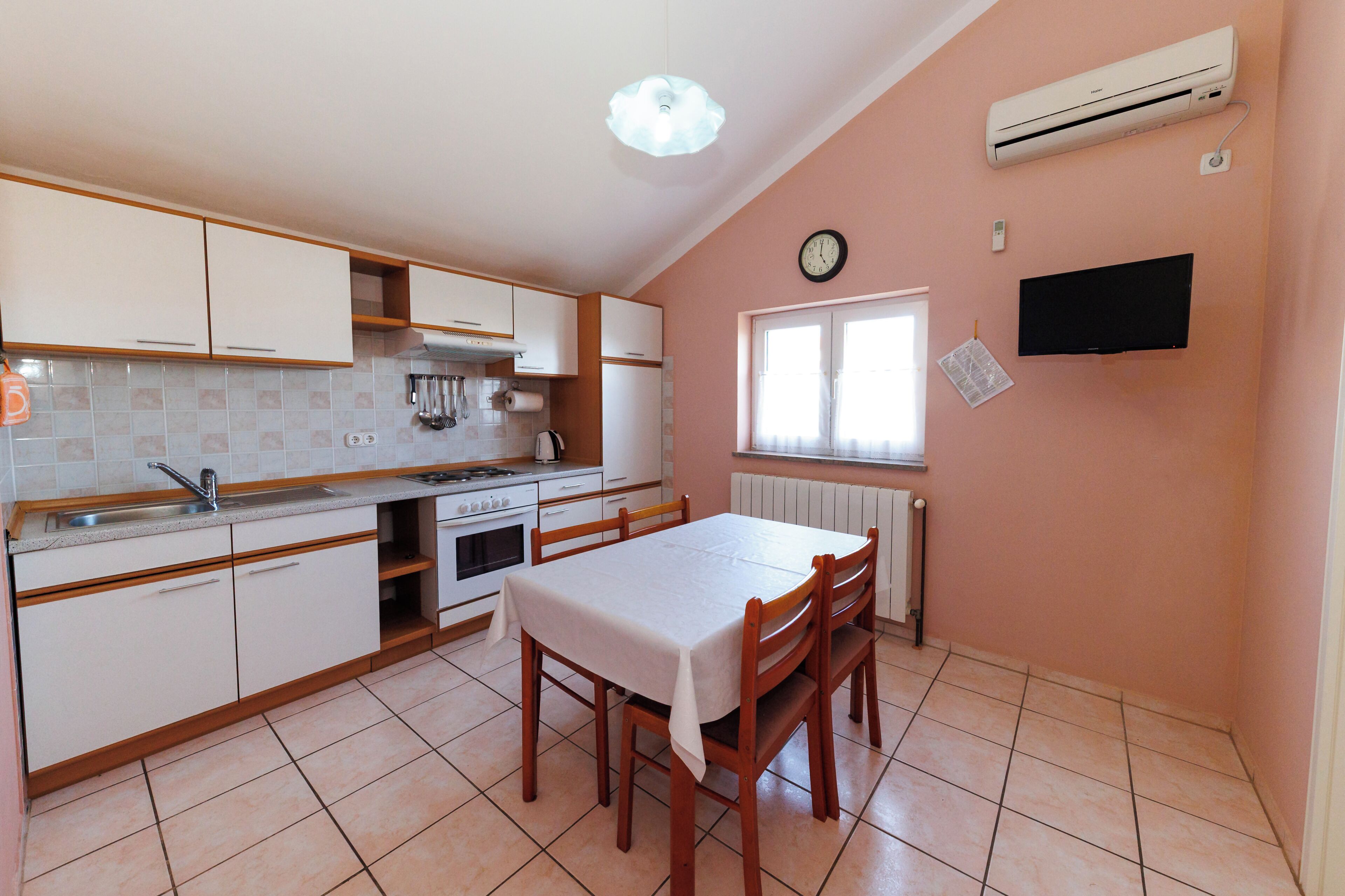 A compact kitchen with white cabinets, a stove, and a dining table with chairs.