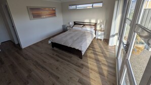 Ein Schlafzimmer mit einem großen Bett, zwei Nachttischen, einem Deckenventilator und einem Fenster mit Jalousien.