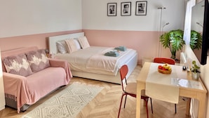 A bedroom with a bed, a sofa, a dining table, and a chair. There are three framed pictures on the wall. - Lovely self-contained studio in Roissy-en-France / Aeroport CDG with airport terrace (Roissy-en-France)