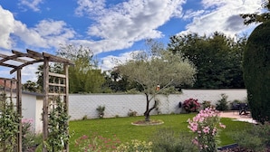 A garden with a wooden pergola, a white wall, and various plants and flowers. - Lovely self-contained studio in Roissy-en-France / Aeroport CDG with airport terrace (Roissy-en-France)