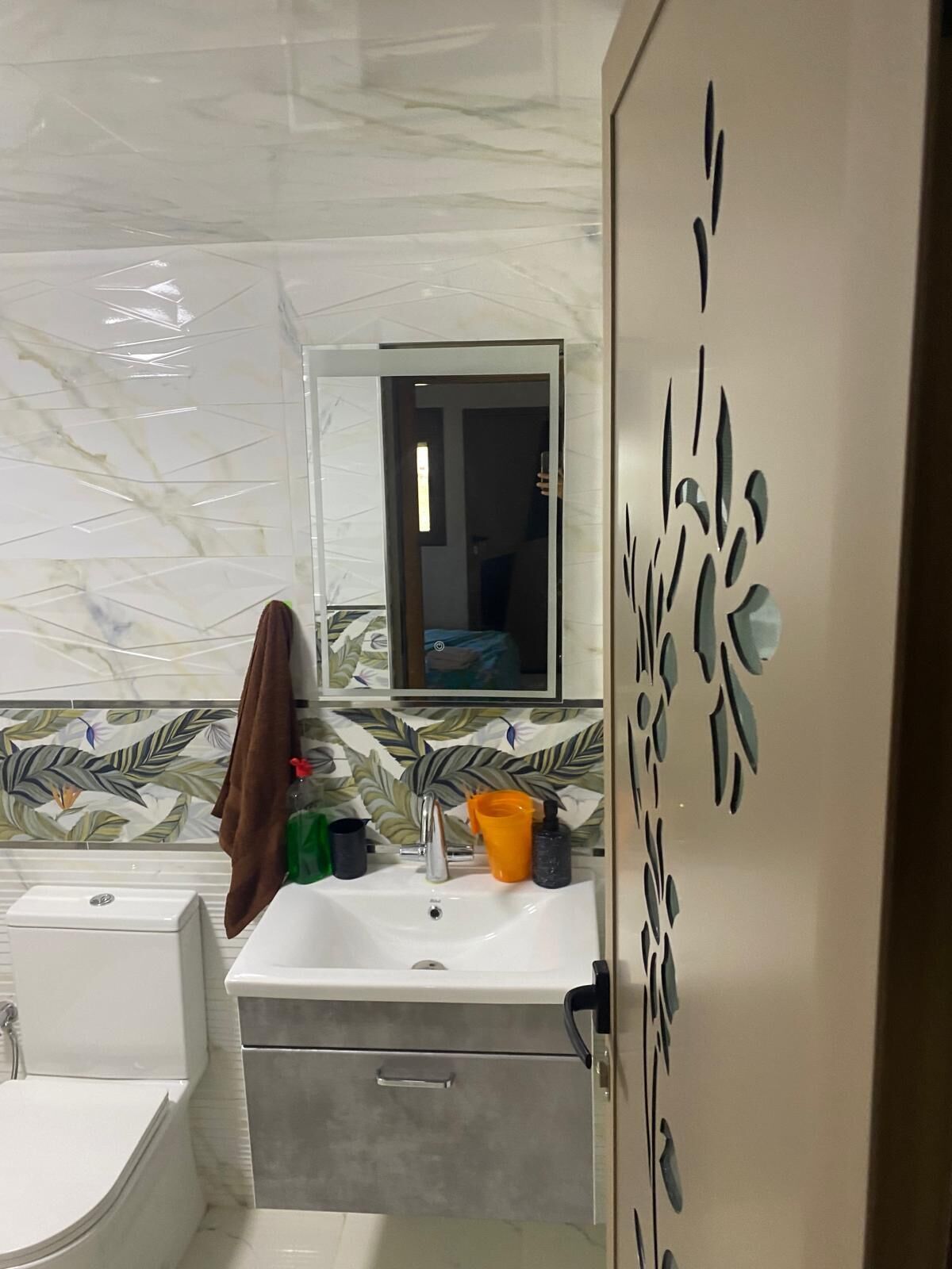 A bathroom with a white sink, a mirror, and a toilet.