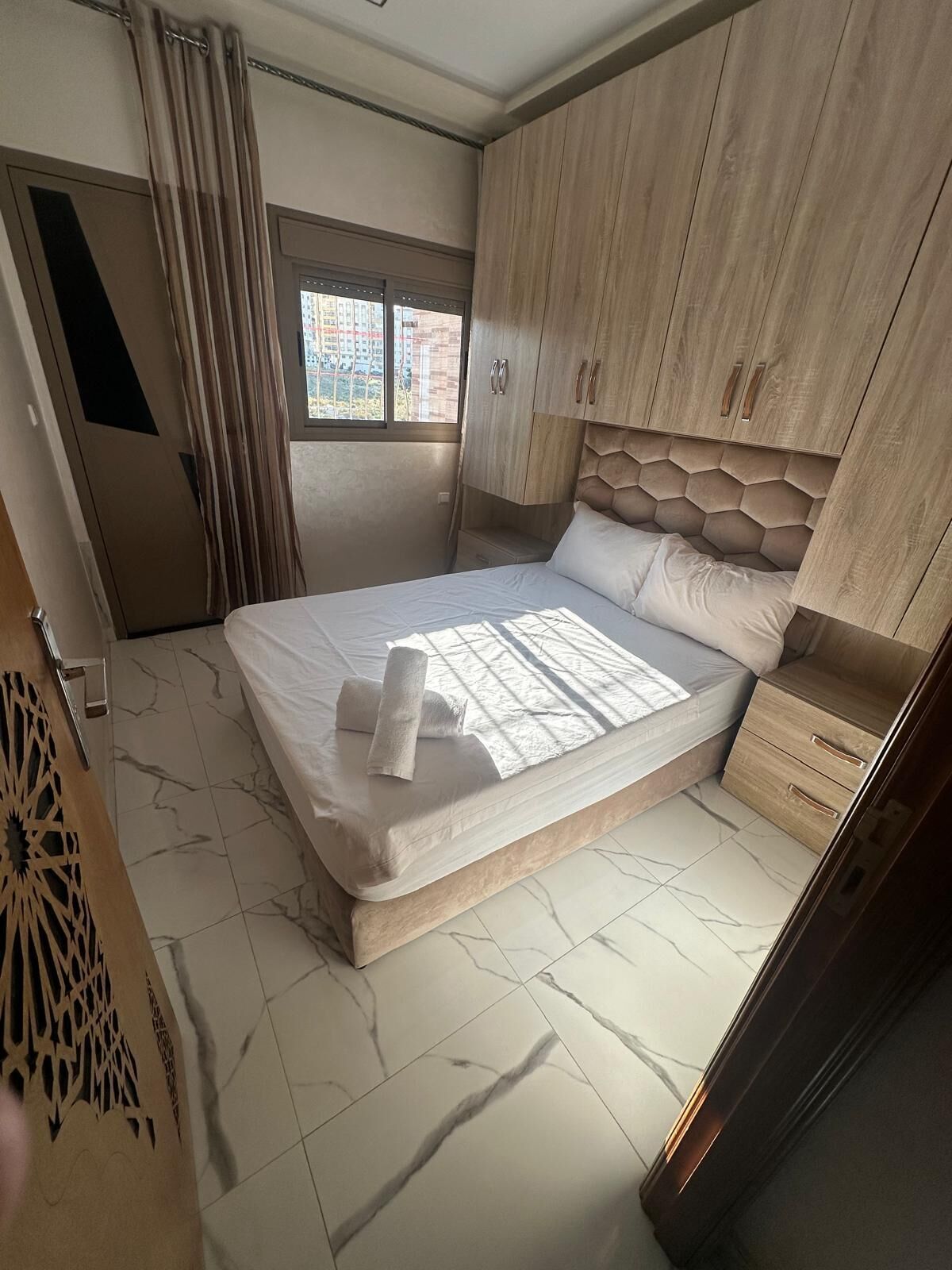 A bedroom with a bed, a window, and a wardrobe.