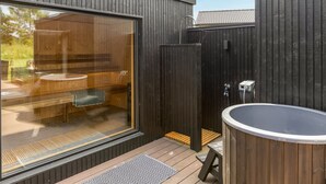 A spa area with a hot tub, wooden deck, and a glass-enclosed room with a bench and a small table. - "Artur" - 800m from the sea by Interhome (Glesborg)