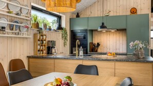 A modern kitchen with wooden cabinets, a central island, and a dining area with a fruit bowl. - "Artur" - 800m from the sea by Interhome (Glesborg)