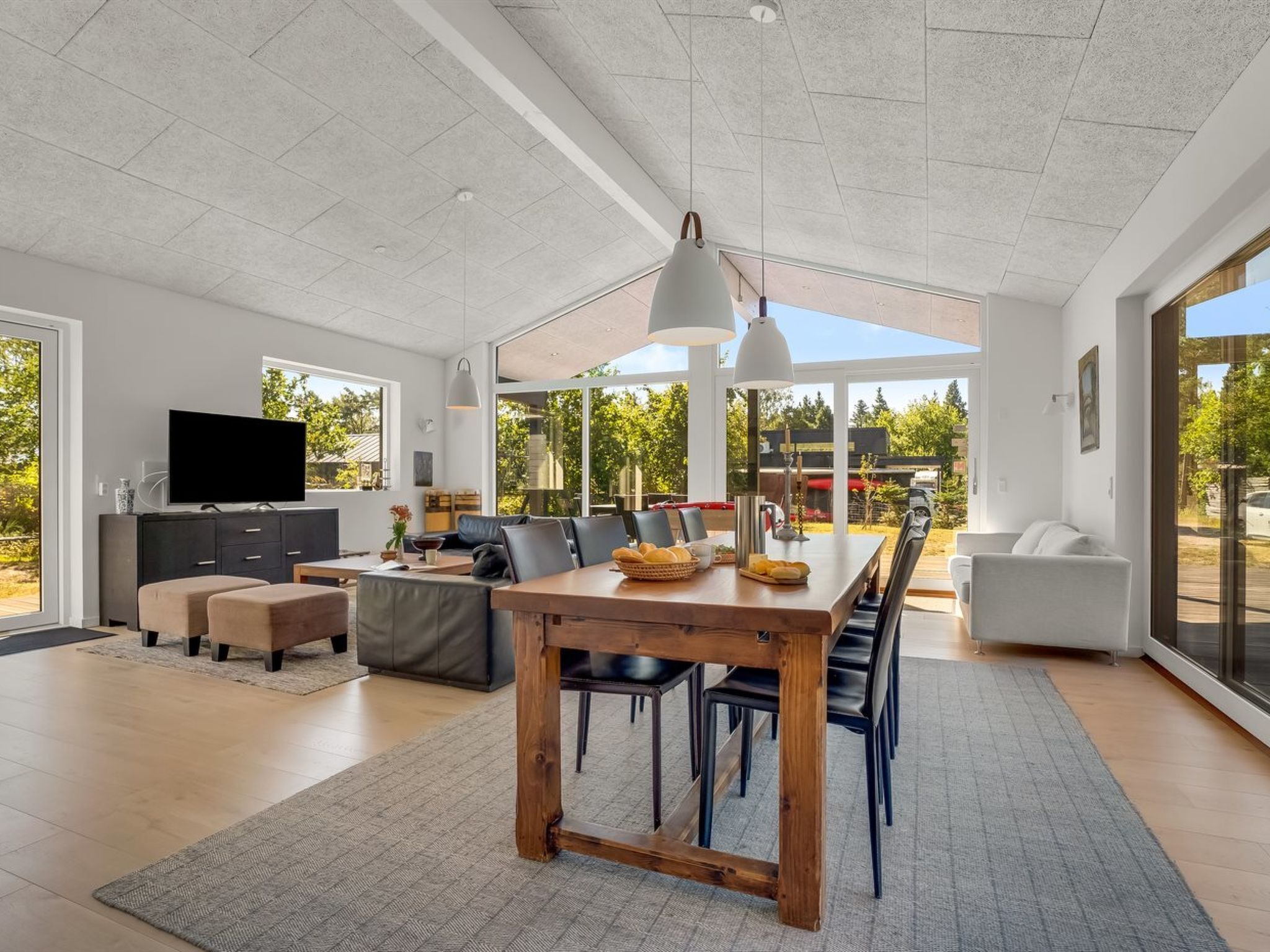 A spacious living area with a wooden dining table, comfortable seating, and a large TV.