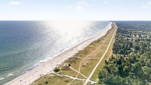 Luftaufnahme einer Küstenlandschaft mit Strand, einer Straße und einem bewaldeten Gebiet.