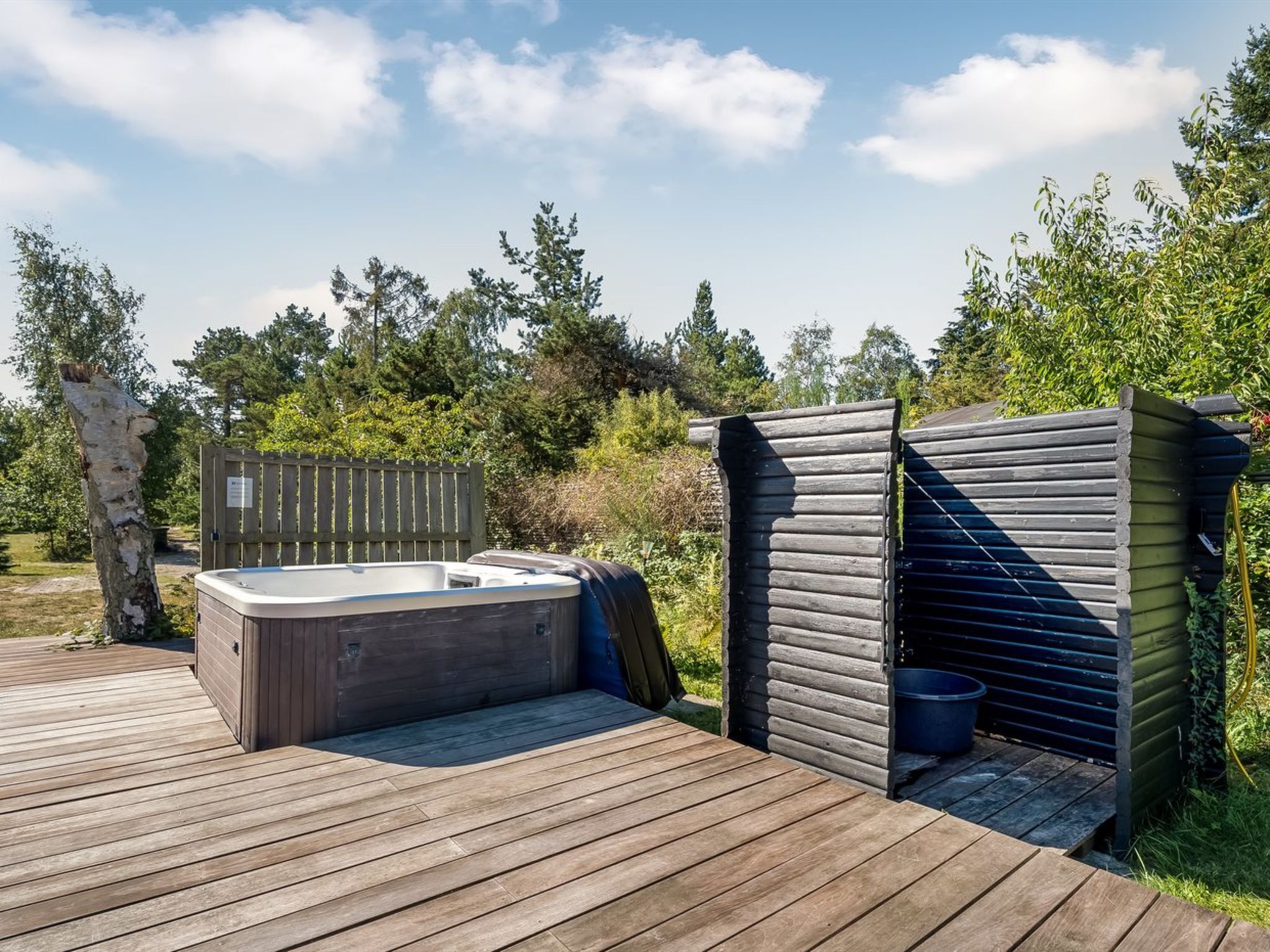 Une terrasse en bois avec un jacuzzi et un sauna.