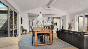 Ein modernes Wohnzimmer mit einem Holzespeiseplatz, einer schwarzen Ledersofa und einer Küche im Hintergrund.