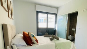 Une chambre à coucher moderne avec un lit, une lampe de chevet et une vue sur l’extérieur.