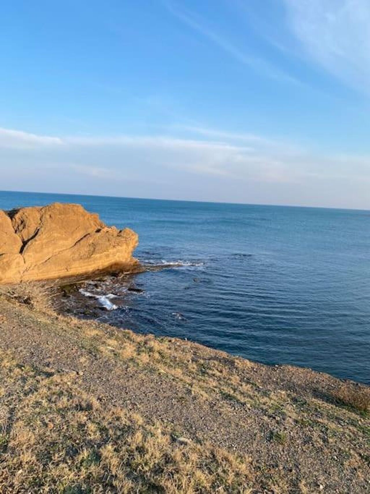 Un paysage côtier avec un promontoire rocheux et une mer calme.