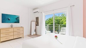 Un dormitorio con cama, cómoda, televisor y balcón con vistas.