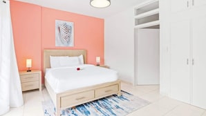 Un dormitorio con cama, mesitas de noche, lámpara de techo, armario y un cuadro en la pared.