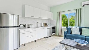 Een moderne keuken met witte kasten, roestvrijstalen apparatuur en een blauwe bank in de woonkamer.