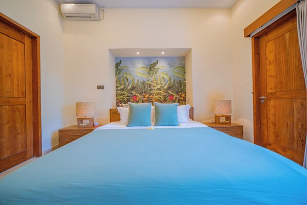 Un dormitorio con una cama grande, cabecera de madera y un mural tropical en la pared.