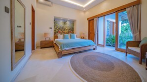 A bedroom with a bed, bedside tables, a large mirror, a painting, and a view through the glass door. - Luxury Balinese style villa with AC in Seminyak- 5BR for ultimate relaxation (Bali)