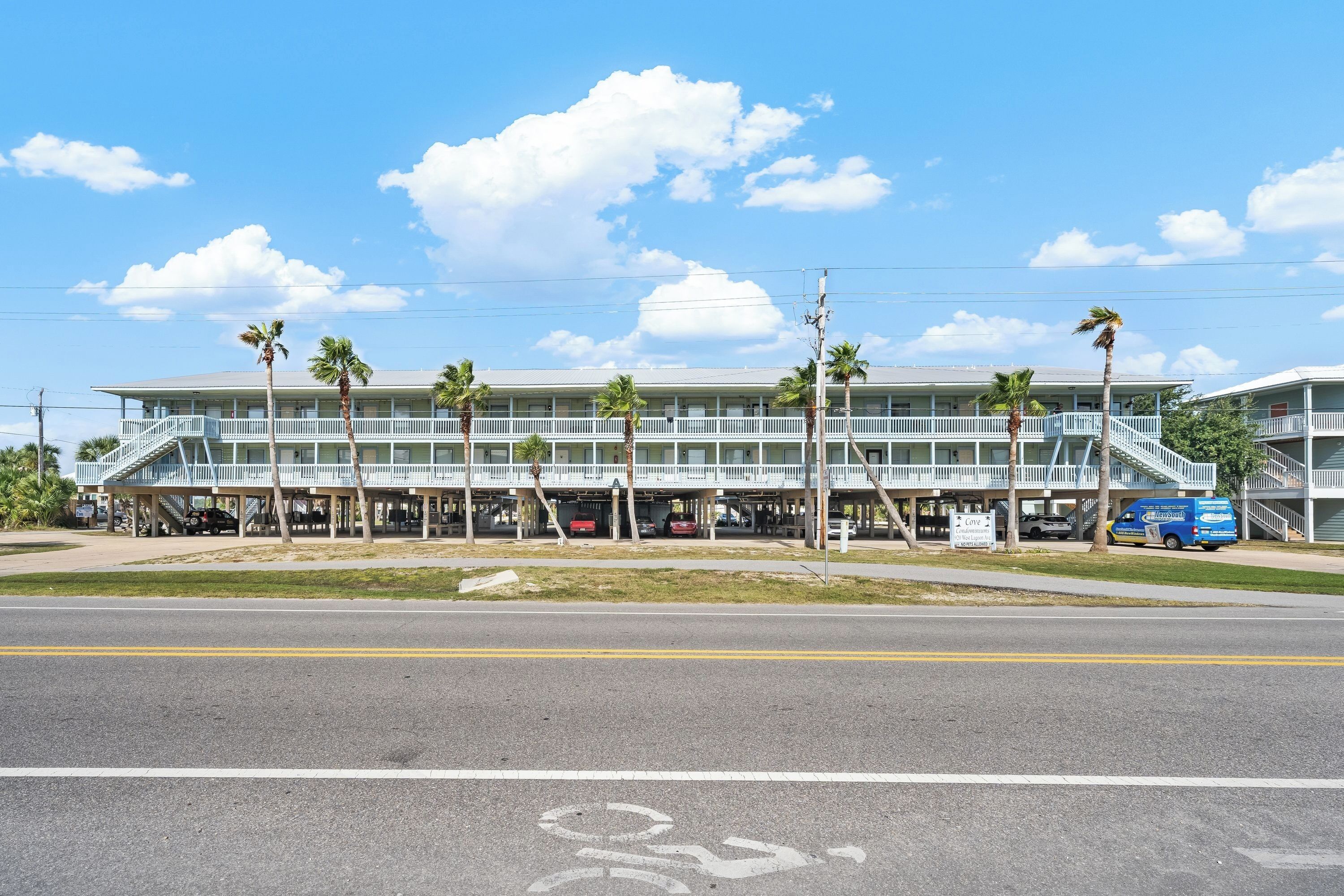 A multi-story building with a covered walkway and parking area.