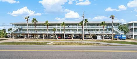 A multi-story building with a covered walkway and parking area.