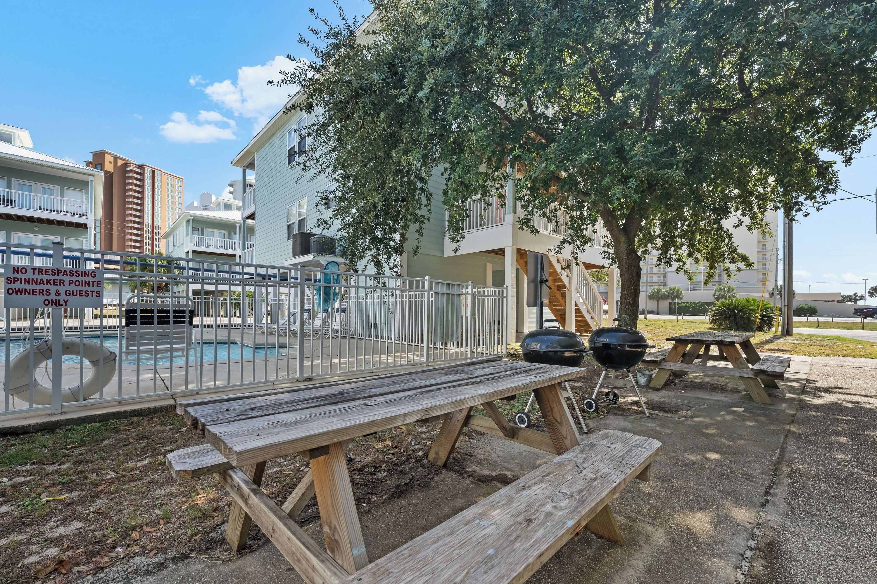 A pool area with a wooden picnic table and barbecue grill, surrounded by a fence with a sign indicating private property for owners and guests only.