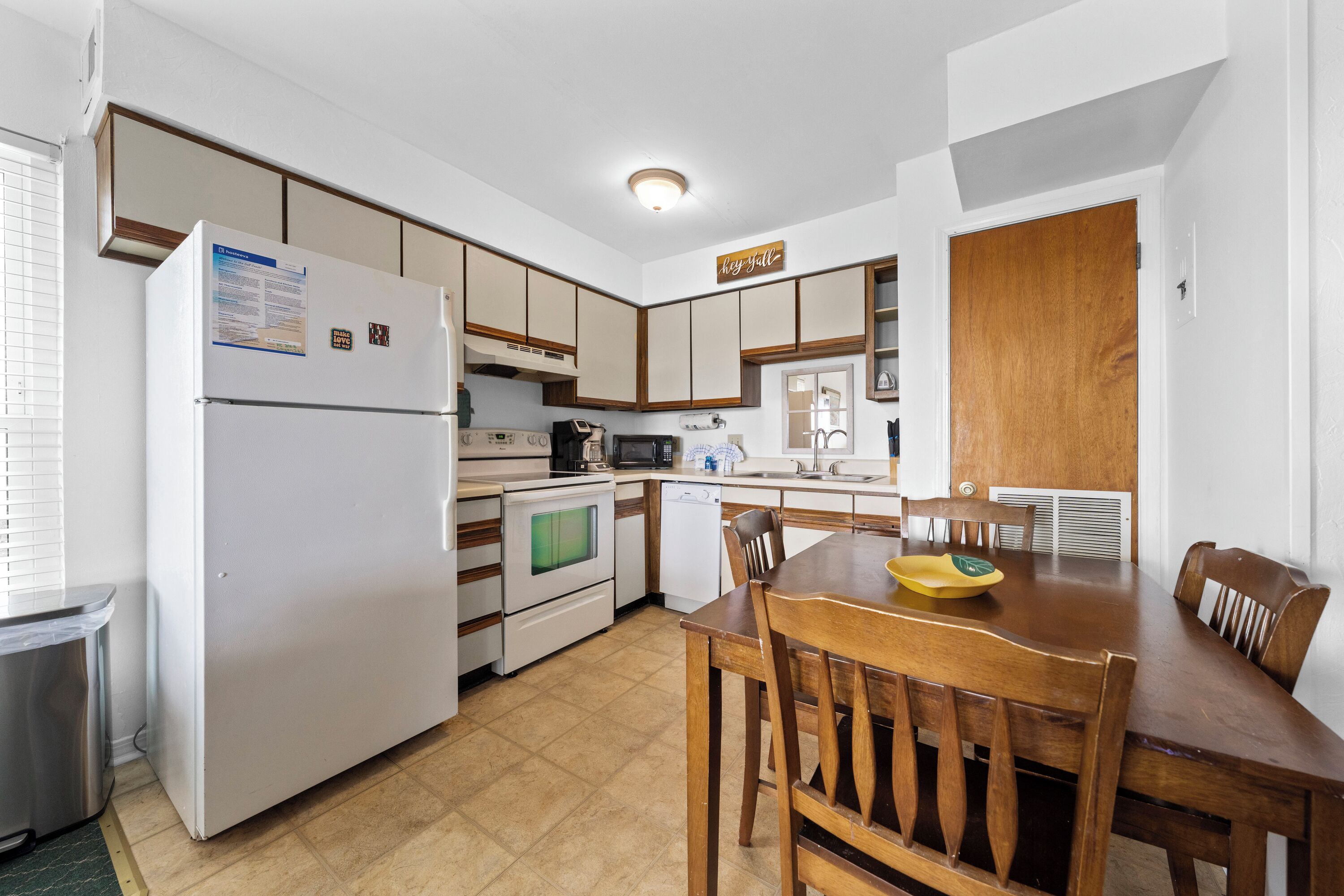 A compact kitchen with a refrigerator, stove, microwave, sink, and wooden dining table with chairs.