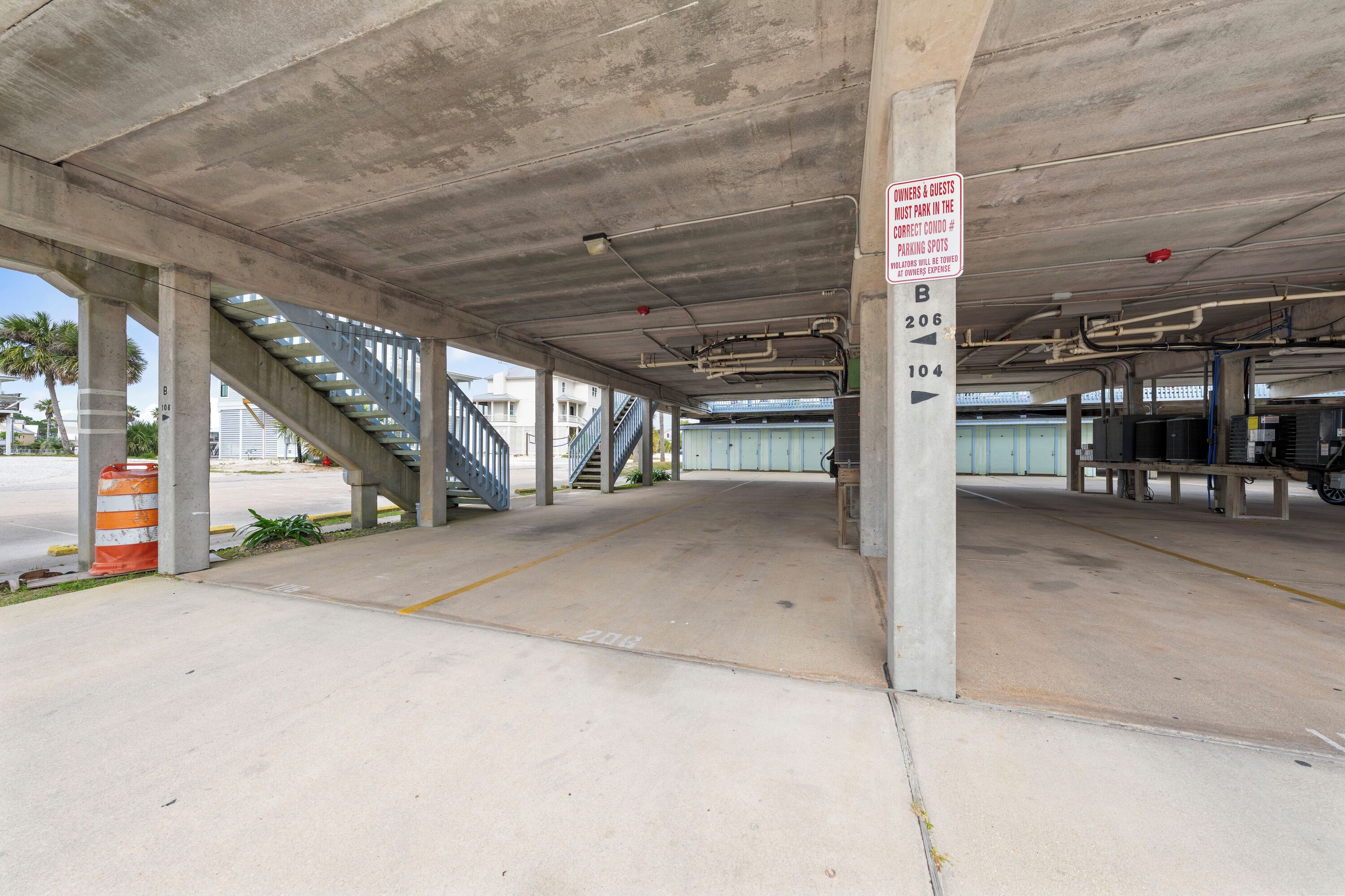 Eine leere Tiefgarage mit Betonpfeilern, einer Treppe und Hinweisschildern.