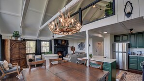 Une salle à manger spacieuse avec une grande table et des chaises en bois, un lustre et une cheminée.