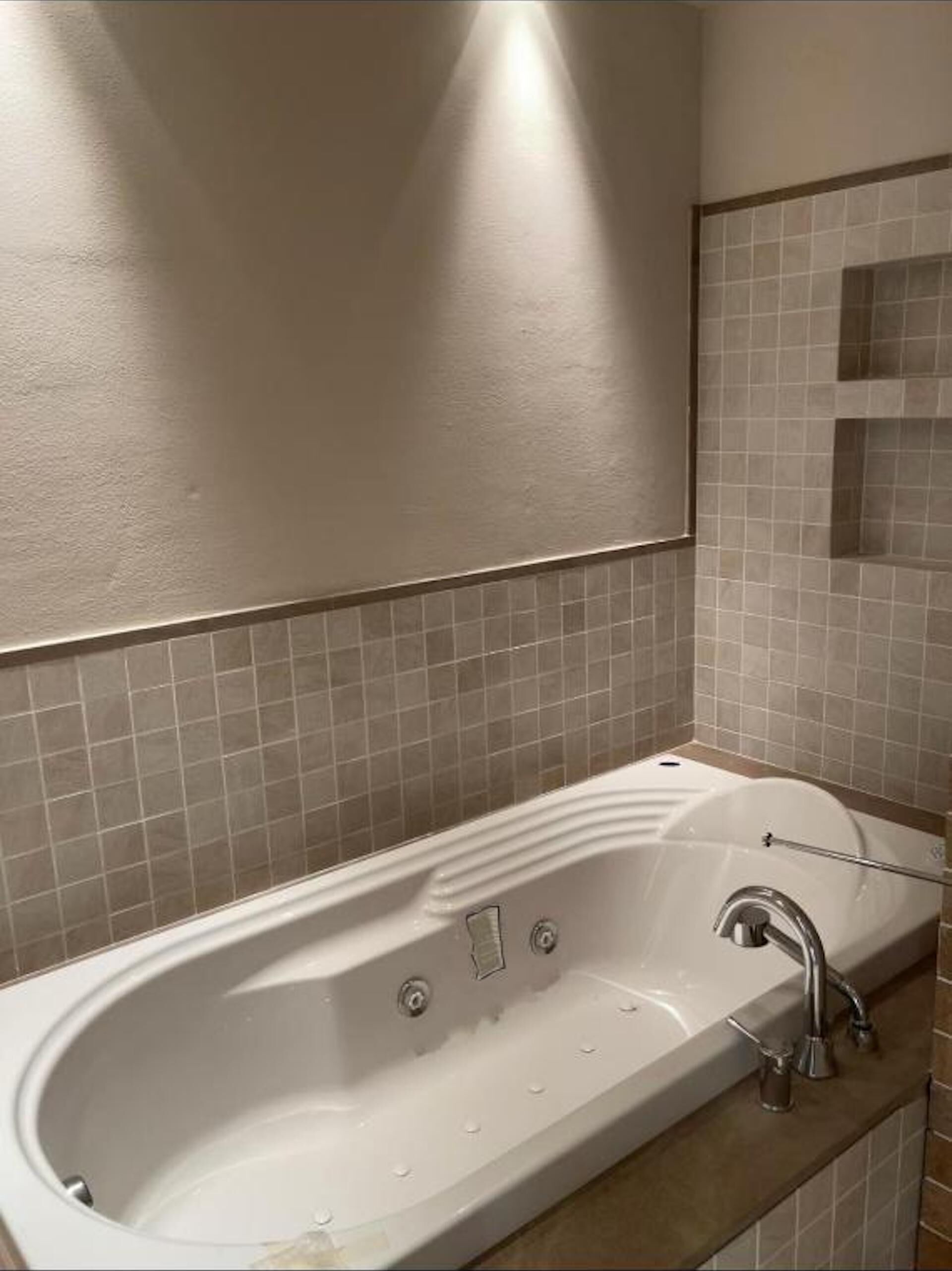 Une salle de bain moderne avec une baignoire sur pieds, un miroir fixé au mur et un pare-baignoire carrelé.