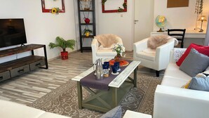 A living room with a TV, sofa, chairs, a coffee table, and decorative items.