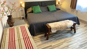 A neatly arranged bedroom with a bed, bedside tables, a bench, and a vase with flowers.