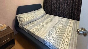 A single bed with a patterned bedspread, a nightstand, a door with a handle, and a ceiling light. - Fabulous building with AC in vibrant Cebu City (Cebu City)