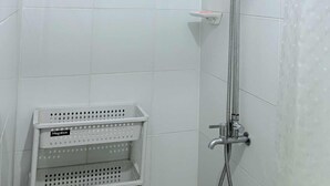 A shower with a handheld showerhead and a fixed showerhead, a Megabox storage basket, and a wall-mounted towel rack. - Fabulous building with AC in vibrant Cebu City (Cebu City)