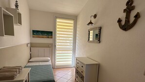 A bedroom with two single beds, a dresser, a mirror, and an anchor decoration on the wall.