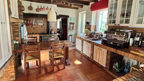 A rustic kitchen with wooden cabinets, a large island, hanging pots, and a vintage stove.