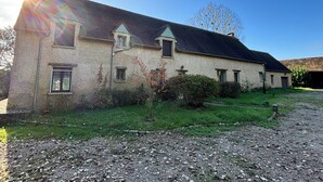 A stone building with a sloped roof, multiple windows, and a gravel driveway.