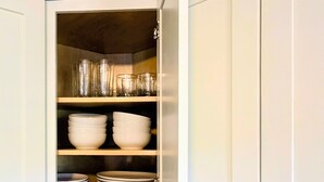 Une cuisine avec des armoires blanches, un comptoir en granit et un four à micro-ondes encastré.