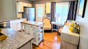 Une cuisine compacte dotée de plans de travail en granit, d’un réfrigérateur et d’un coin repas avec une chaise et une table.