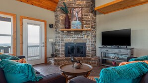 A cozy living room with a stone fireplace, a flat-screen TV, and comfortable seating. - Winston's View: Mountain Views, Fire Pit, Hot Tub (Jasper)