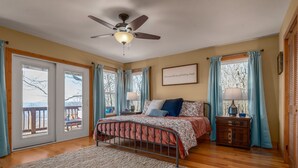A bedroom with a bed, a ceiling fan, a nightstand, and a view through the window. - Winston's View: Mountain Views, Fire Pit, Hot Tub (Jasper)