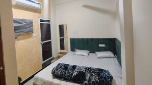 Un dormitorio con cama, ventilador de techo, aire acondicionado y ventana con vista al exterior.