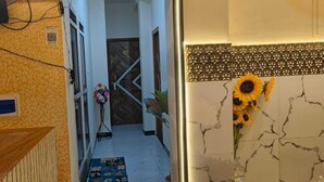 Un pasillo con una mesa de recepción, un cartel con un código QR, una puerta con reja metálica y una pared con diseño decorativo.