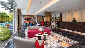 A modern hotel lobby with a reception desk, seating area, and a pool view. - Maitria Hotel Rama 9 Bangkok  (Bangkok)