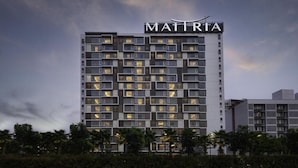A multi-story hotel with a modern facade, featuring a prominent sign at the top. - Maitria Hotel Rama 9 Bangkok  (Bangkok)