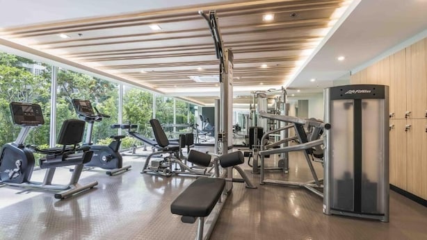 A modern gym with cardio machines, weightlifting equipment, and a bench. - Maitria Hotel Rama 9 Bangkok  (Bangkok)