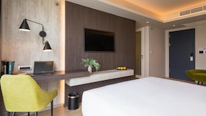 A modern hotel room with a bed, a desk with a laptop, a TV mounted on the wall, and a small plant on the desk. - Maitria Hotel Rama 9 Bangkok  (Bangkok)