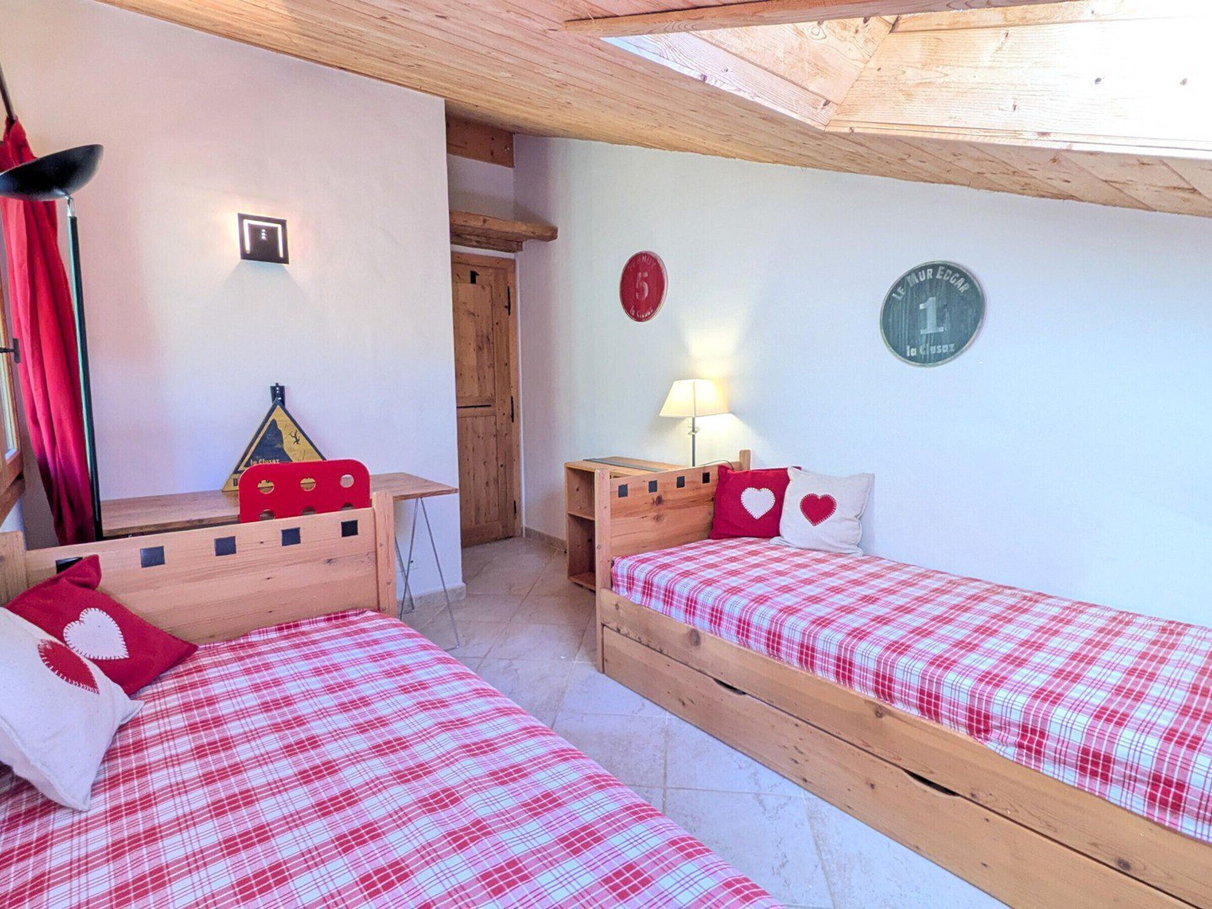 A bedroom with two single beds, a desk, and a chair.