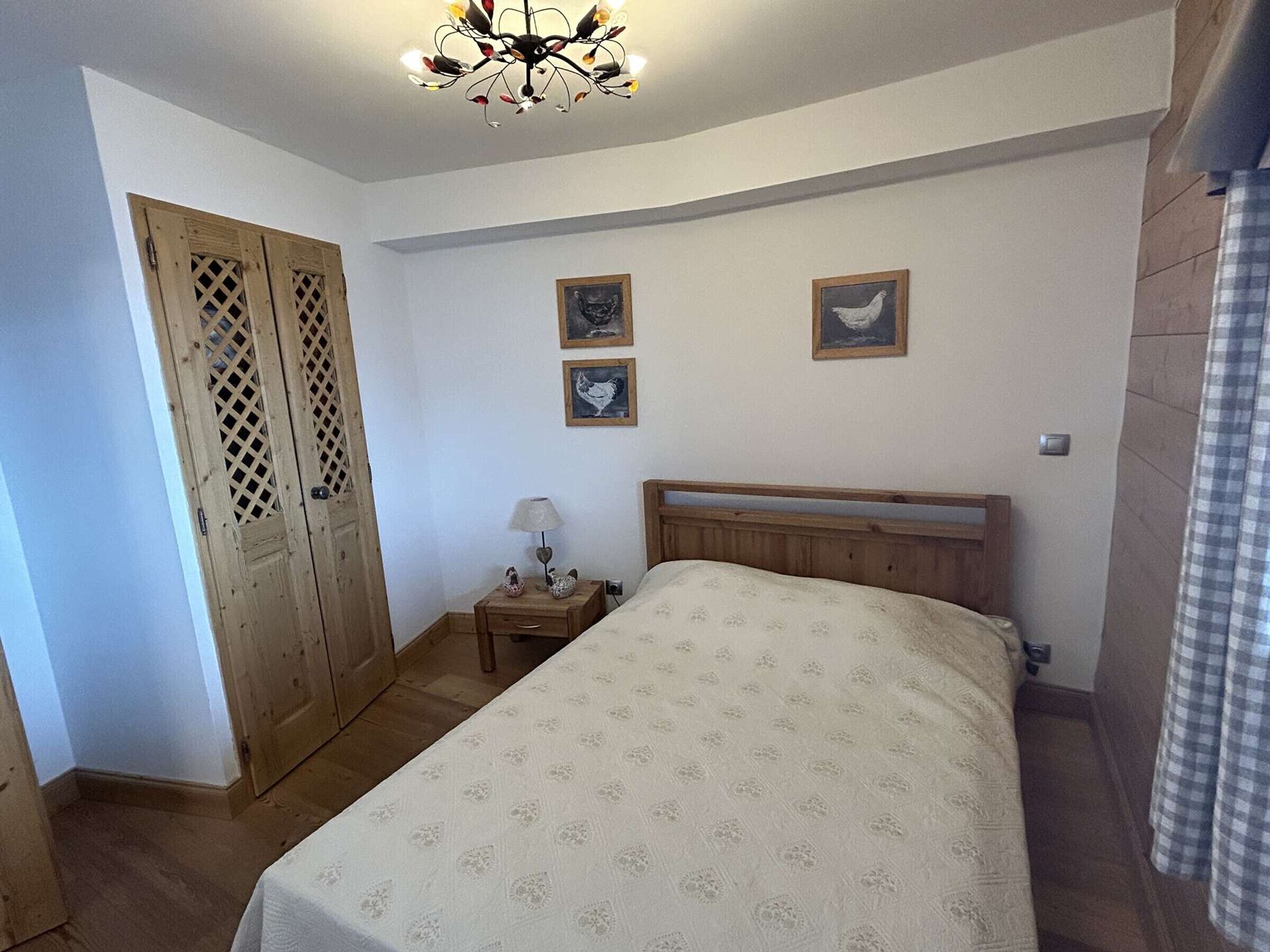 Une chambre à coucher avec un lit en bois, une table de chevet avec une lampe et une porte ornée d’un motif en treillis.