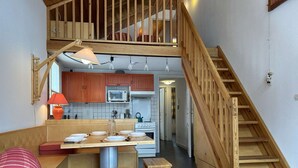 A compact kitchen with wooden cabinets, a microwave, and a stove. There is a wooden staircase leading to an upper level. - Duplex chalet 6-8 ppl, garage, WiFi, Montgenèvre (Montgenèvre)